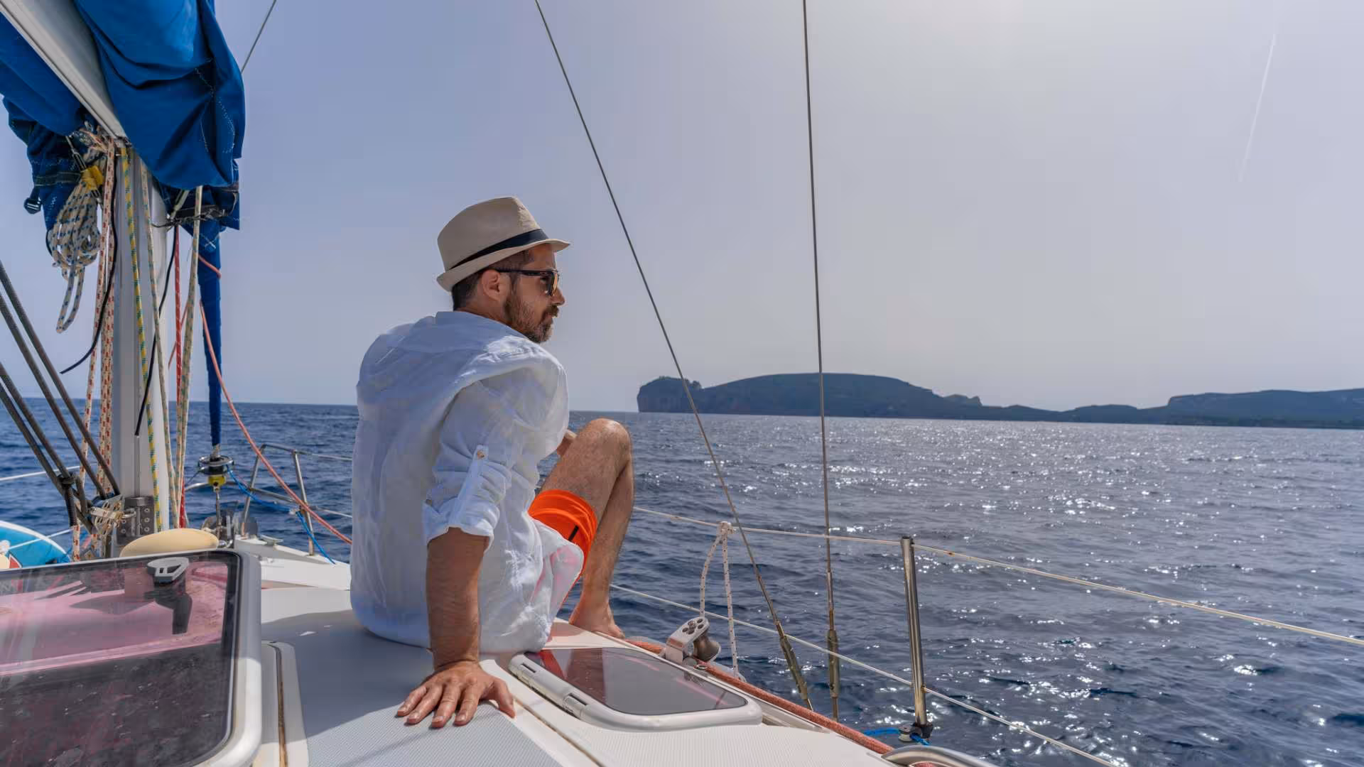 Man relaxing on a yacht deck during a sailing tour in Porto Conte Park near Alghero, enjoying the scenic views.