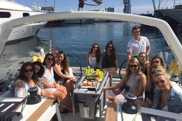 Group enjoying a sunny 3-hour sailing trip with tapas and drinks on a stylish yacht in a picturesque harbor setting.