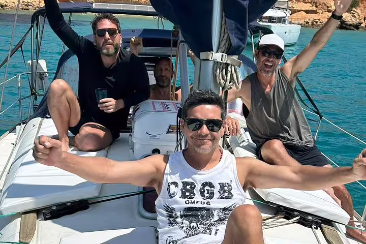 Group of friends enjoying a vibrant sailing adventure in Ibiza and Formentera, relaxing on a yacht with stunning turquoise waters.