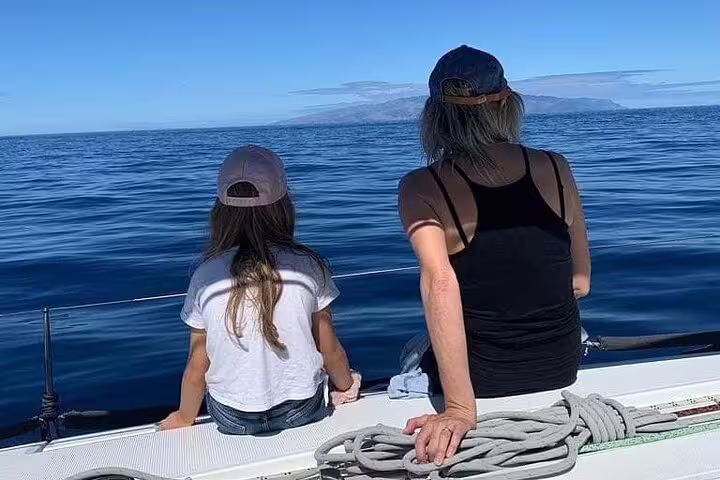Two people enjoying a serene ocean view from a sailing yacht deck, ideal for a private charter experience.