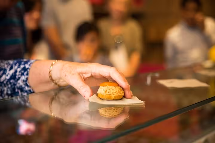 A hand selecting a gourmet pastry during the Saint Germain private food tour with a French gastronomy expert.