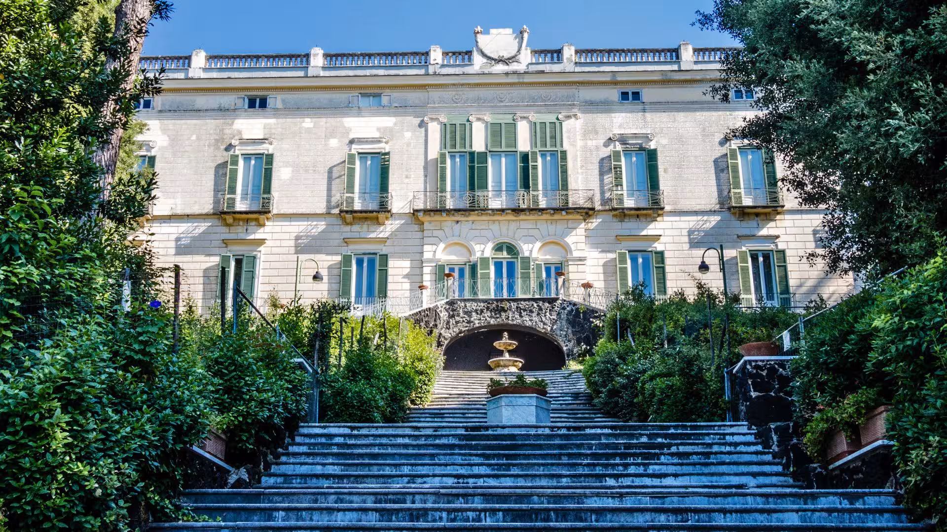 Elegant facade of Saint Martino Belvedere in Vomero, surrounded by lush greenery and historic charm.
