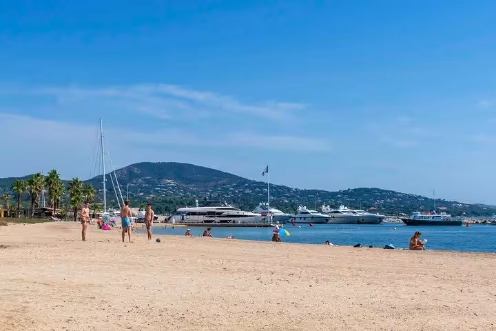 Sunny beach in Saint-Tropez with yachts and mountains, ideal for a relaxing day on a private full day tour.