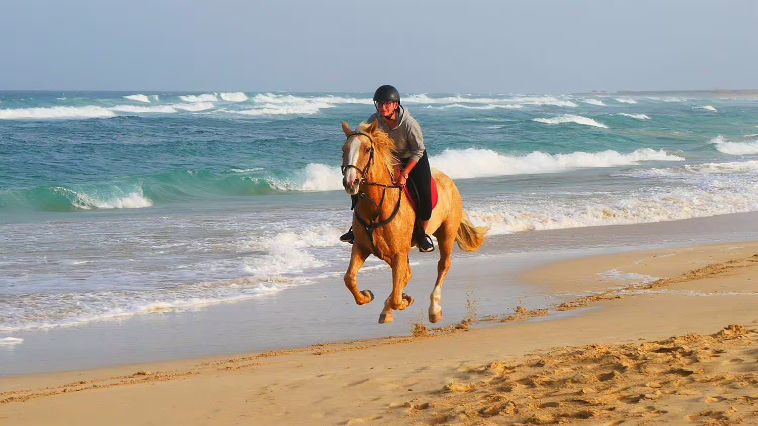 Horse riding along the scenic Sal beach with waves crashing, part of the Salt Flats & Sand Dunes Adventure tour.
