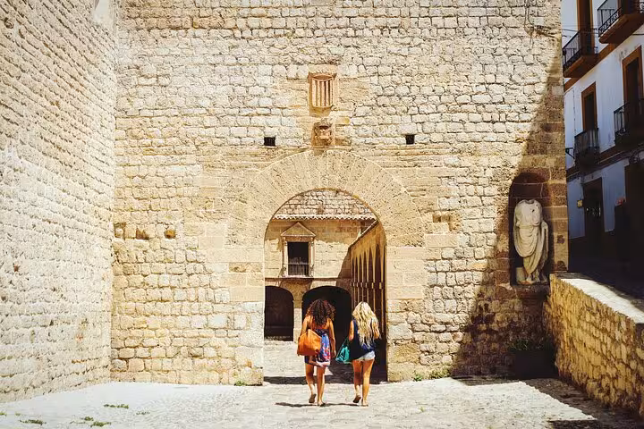 Tourists exploring a historic stone gateway in Salamanca, experiencing the city's rich architectural heritage on a guided tour.