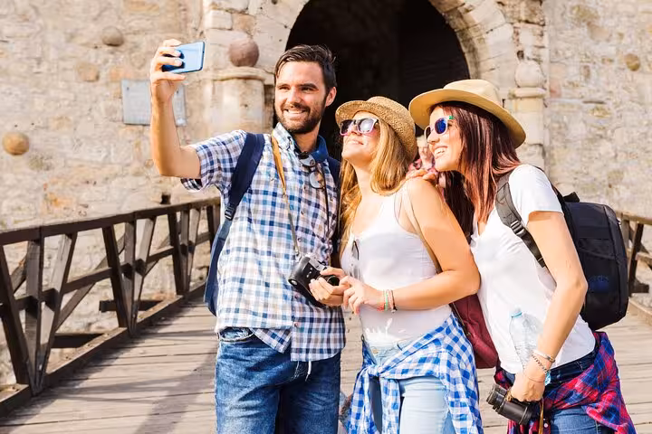 Group of tourists taking a selfie in front of a historic stone bridge in Salamanca, enjoying a private guided city walk.