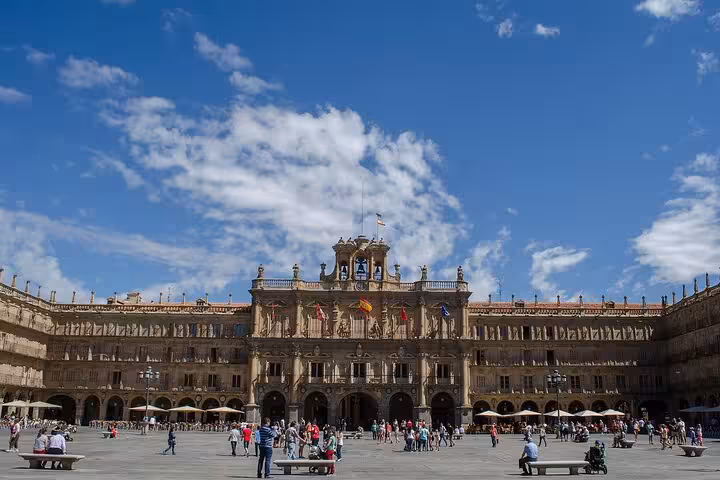 Vibrant Plaza Mayor in Salamanca bustling with tourists under a bright blue sky on a guided city walk.
