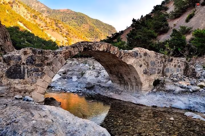 Stone arched bridge over stream on Samaria Gorge full day tour from Rethymno, Crete hiking trip