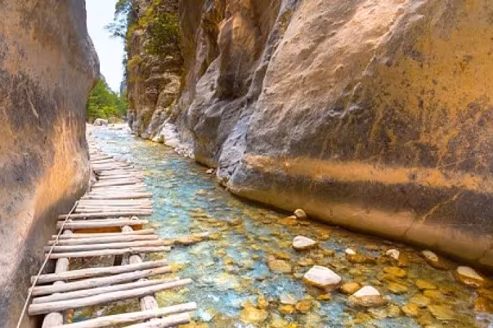 Wooden footpath over clear river in Samaria Gorge, Crete, on full-day hiking tour from Rethymno