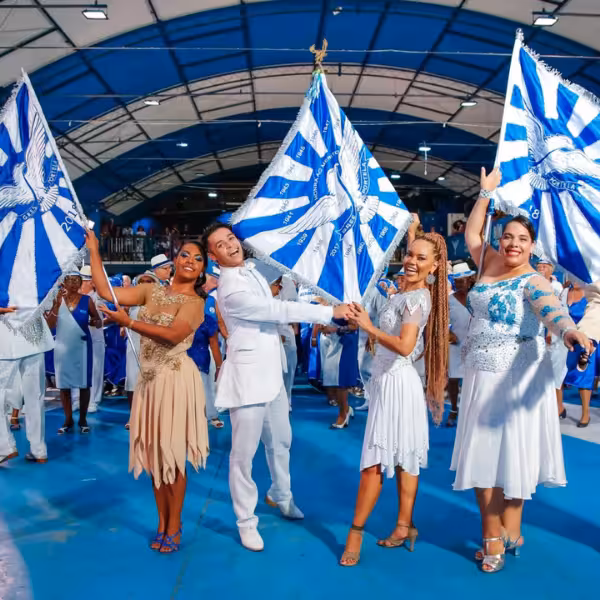 Samba dancers in colorful costumes waving flags during a lively Rio de Janeiro carnival rehearsal, showcasing cultural vibrance.