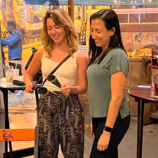 Two women enjoying musical instruments during Samba Night Experience in Lapa, surrounded by vibrant nightlife.