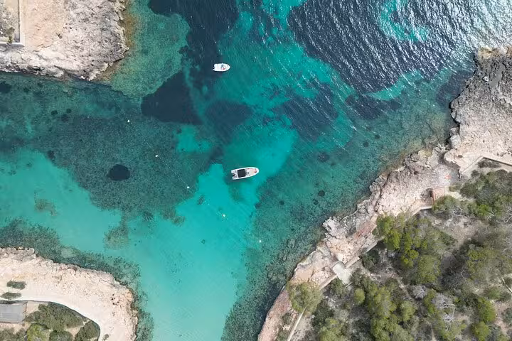Aerial view of boats in turquoise waters surrounded by rocky cliffs on a San Antonio boat tour.