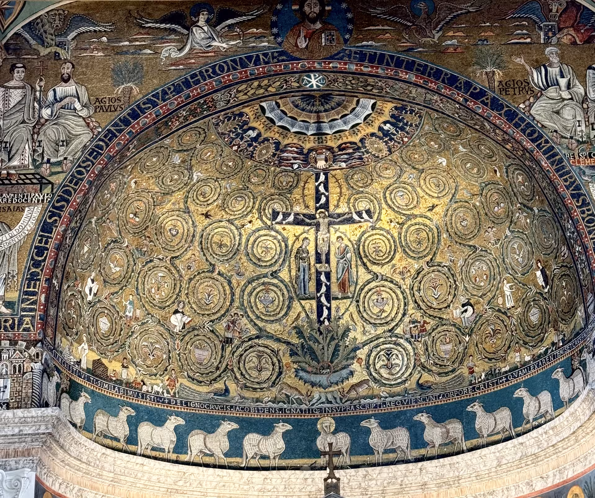 Golden apse mosaic with cross, saints and lambs inside Basilica di San Clemente, showcasing early Christian art in Rome