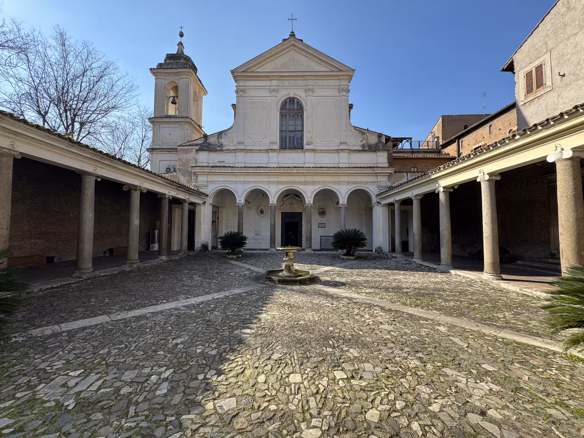 Sunny courtyard and facade of San Clemente Basilica in Rome, starting point for underground temples and secret ruins tour