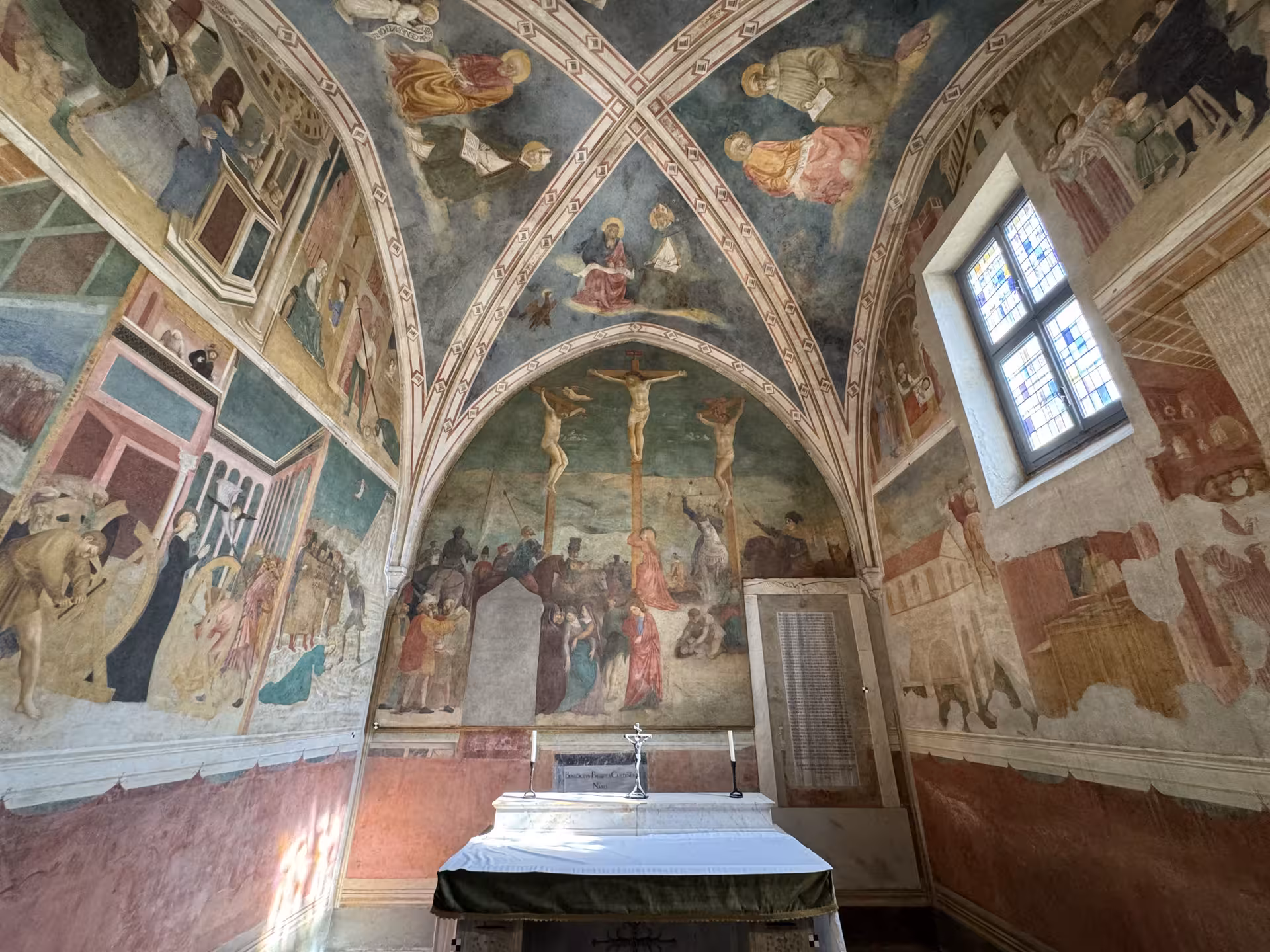 Frescoed medieval chapel inside San Clemente Basilica in Rome, with vivid crucifixion murals and altar on an underground tour