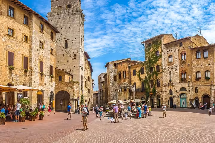 Picturesque square in San Gimignano bustling with tourists and medieval architecture.