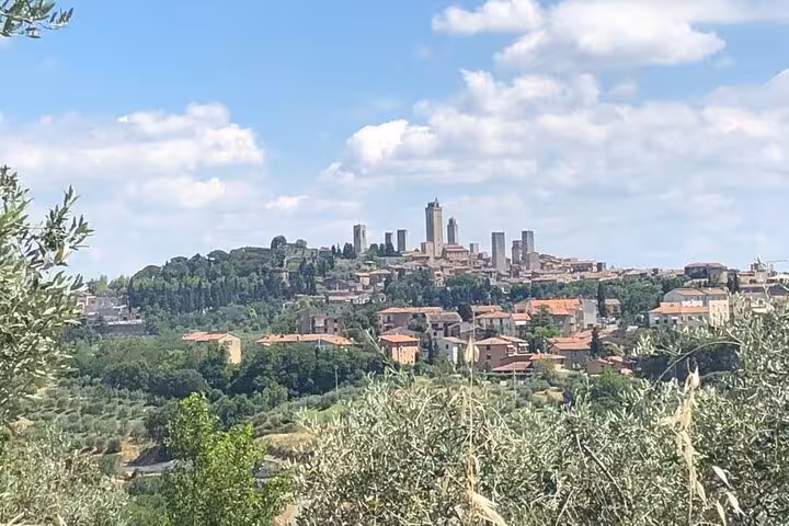 Scenic view of San Gimignano's medieval towers surrounded by lush Tuscan countryside from a vantage point.