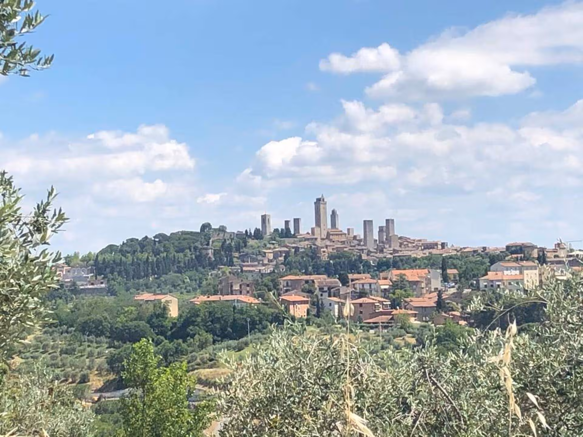 Scenic view of San Gimignano with its iconic medieval towers rising against a sunny blue sky in Tuscany.