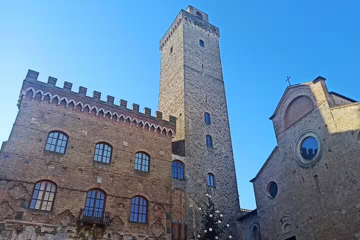 Historic stone palazzo and bell tower in San Gimignano’s main square visited on a private Volterra and wine tasting tour