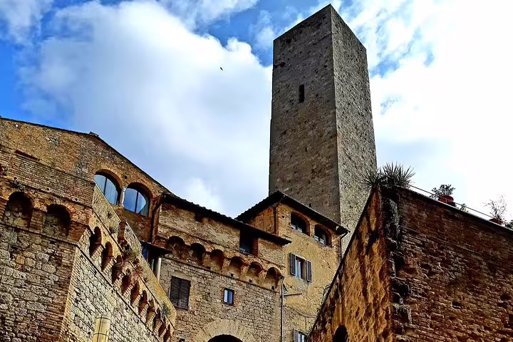 Medieval stone tower and ancient walls of San Gimignano under a bright Tuscan sky on a private shore excursion from Livorno