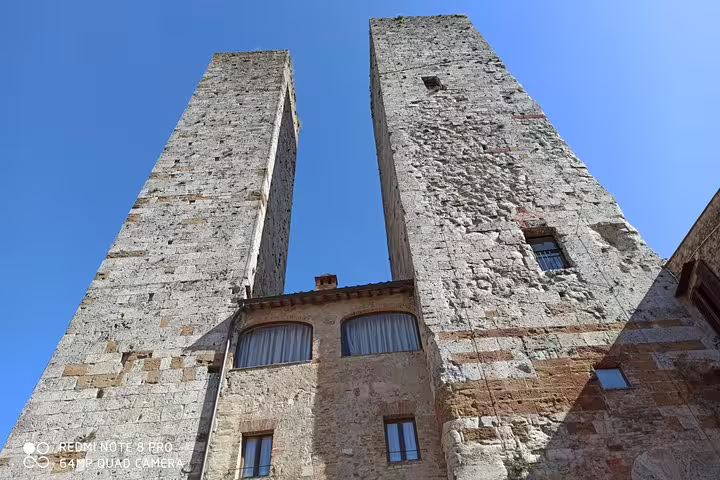 Twin medieval towers of San Gimignano rising above historic houses, visited on a private Tuscany day trip from Livorno Port