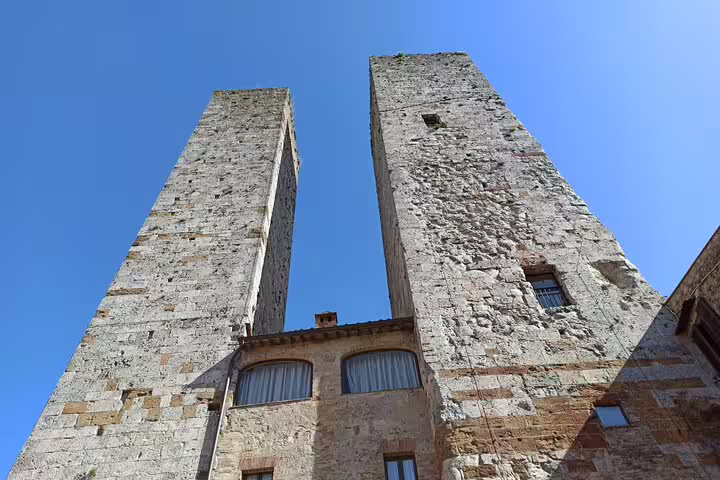 Upward view of San Gimignano’s iconic stone towers against a clear blue sky on a private Tuscany sightseeing tour