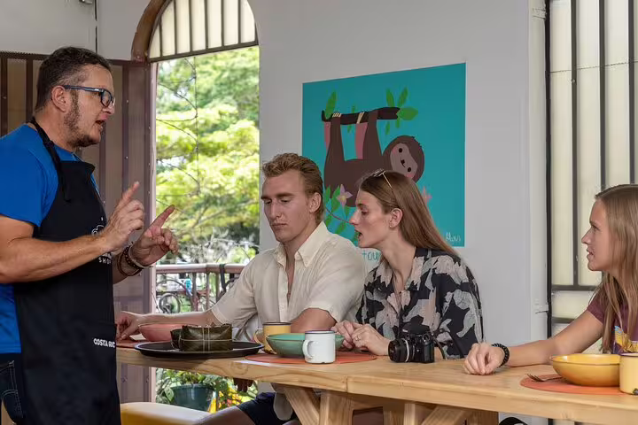 Tourists enjoy a culinary lesson during the San Jose food tour, surrounded by vibrant decor and local dishes.