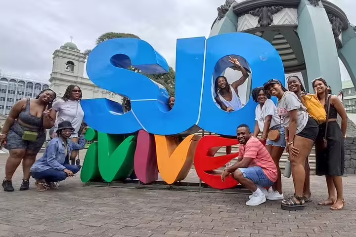 Group posing by colorful SJO Vive sign in San Jose, enjoying the Bites and Sights Walking Food Tour experience.