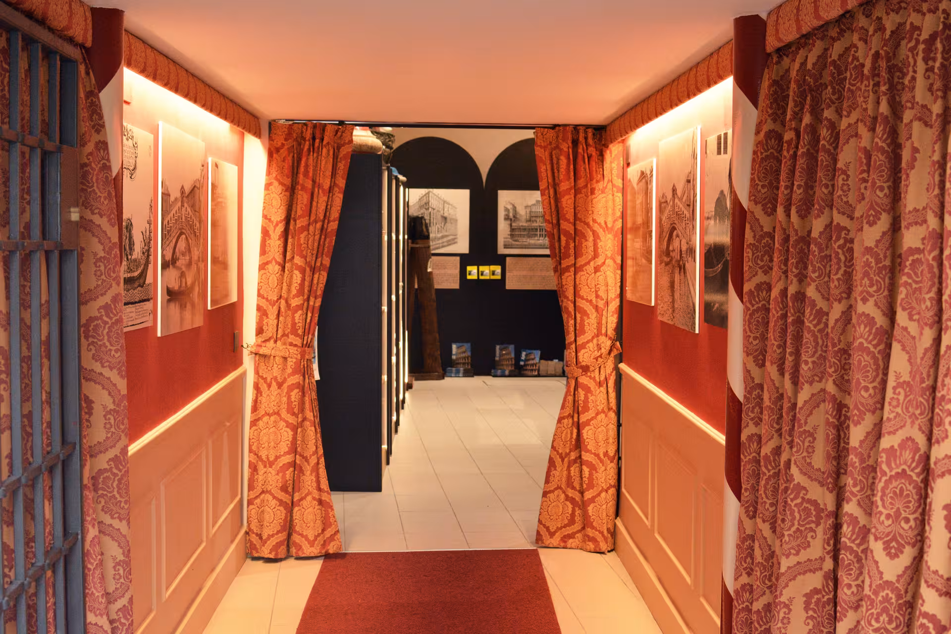 Entrance to San Marco History Gallery in Venice with ornate red curtains and historic artwork lining the walls.