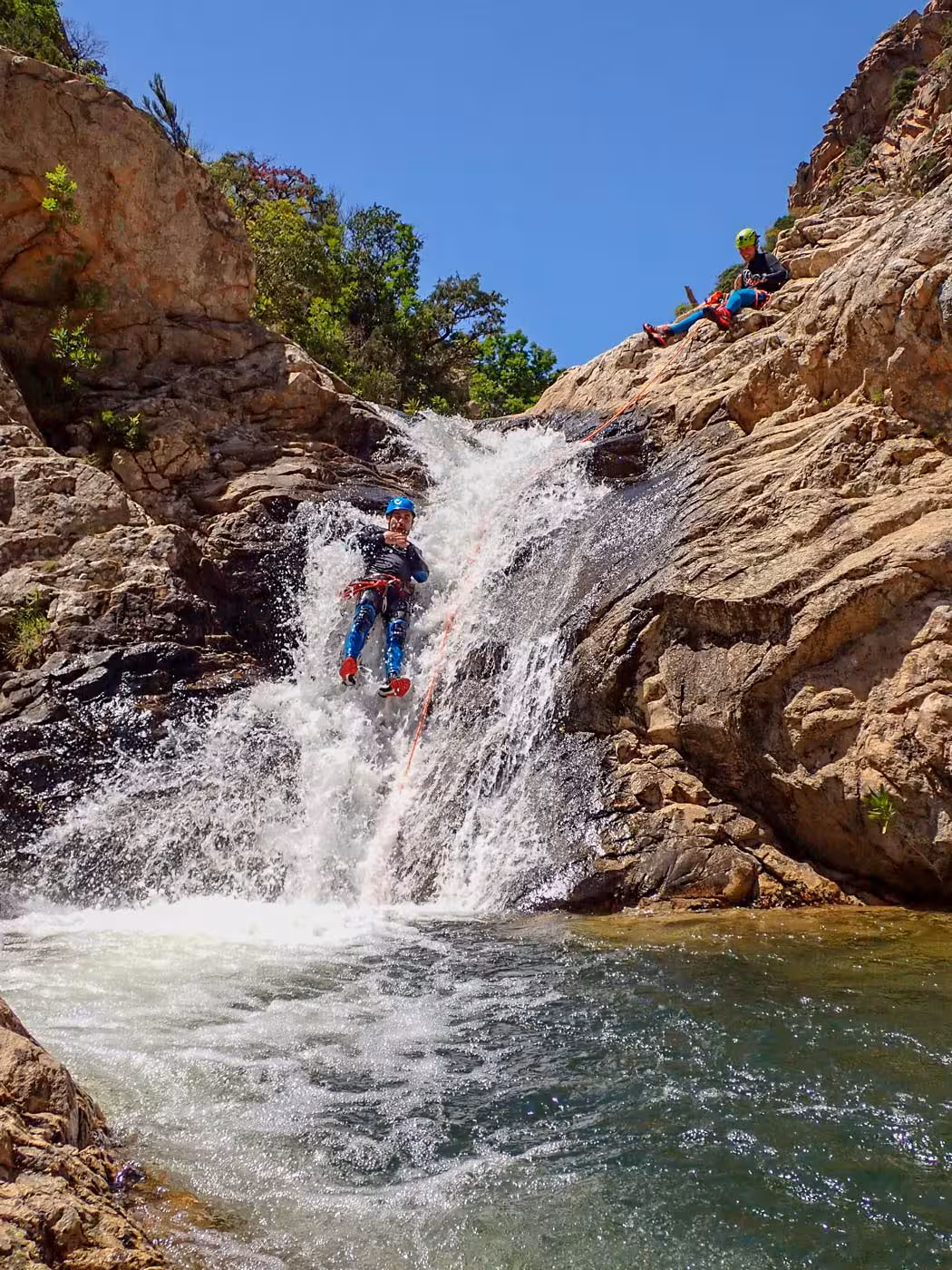Adventurer rappelling down Rio Pitrisconi waterfall in San Teodoro, showcasing thrilling canyoning experience.