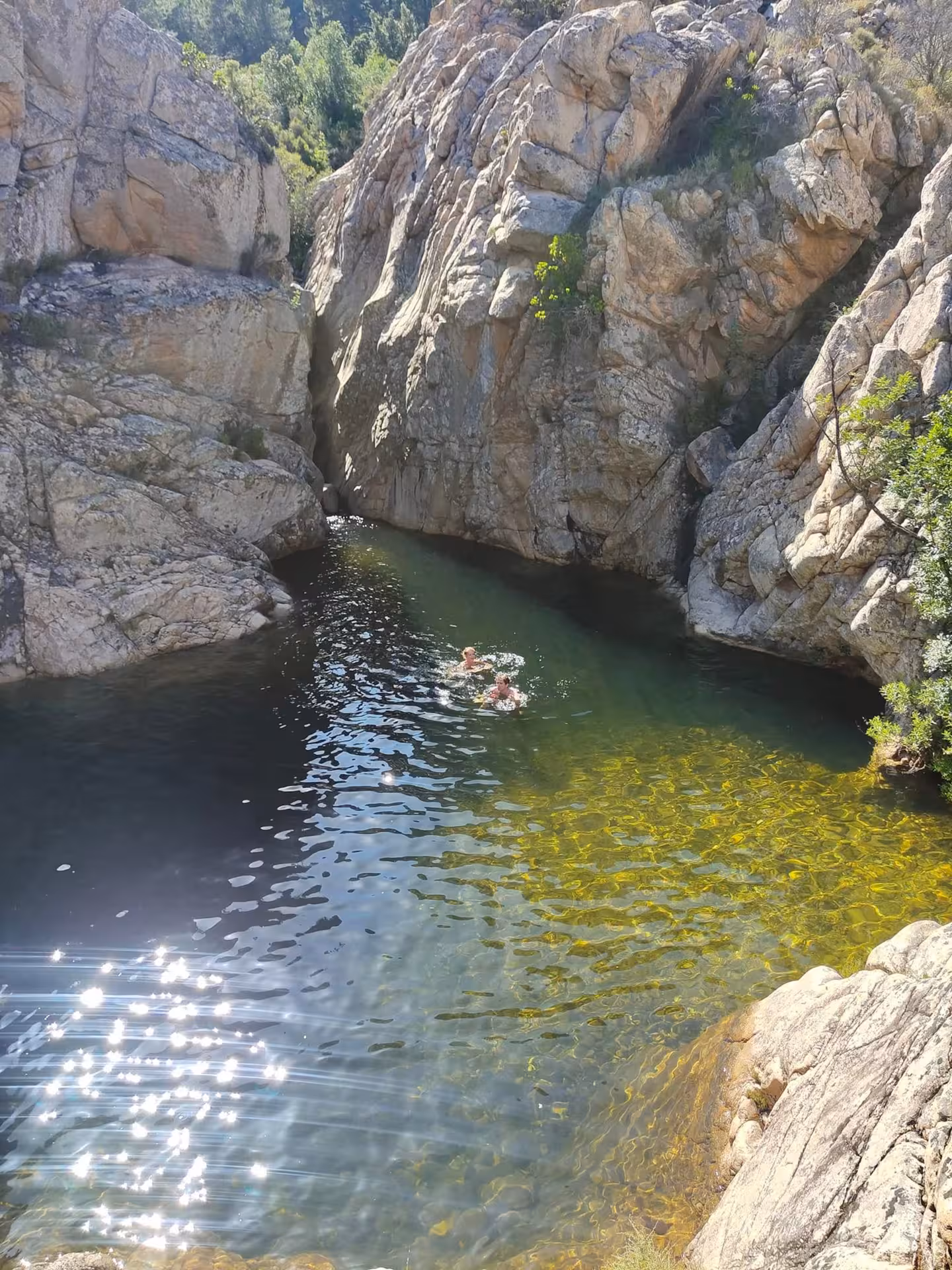 Tourists swimming in the crystal-clear waters of Rio Pitrisconi surrounded by rugged cliffs on a jeep tour from San Teodoro.