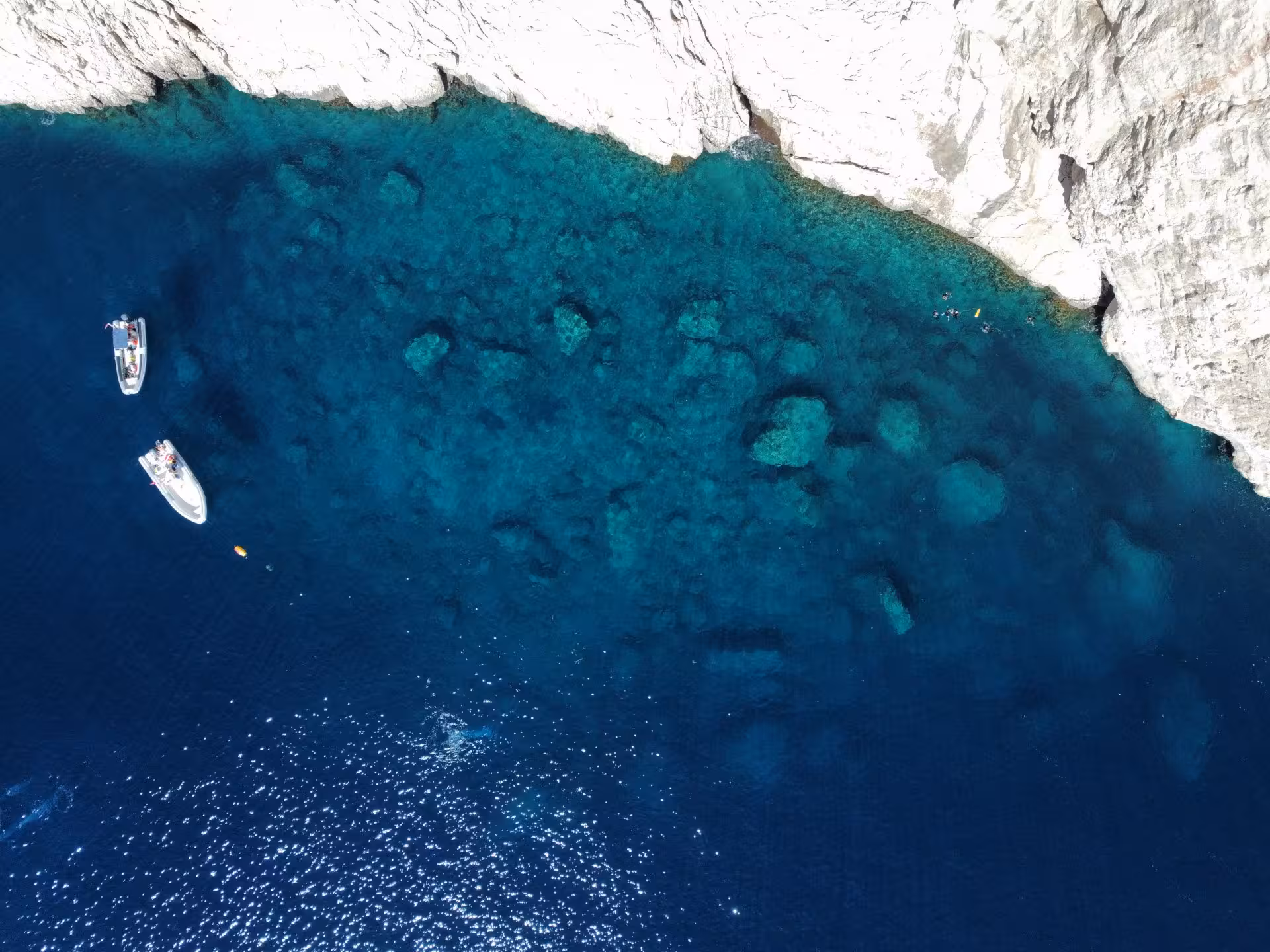 Aerial view of Molara's crystal-clear waters with boats and rocky cliffs, ideal for a San Teodoro snorkeling adventure.