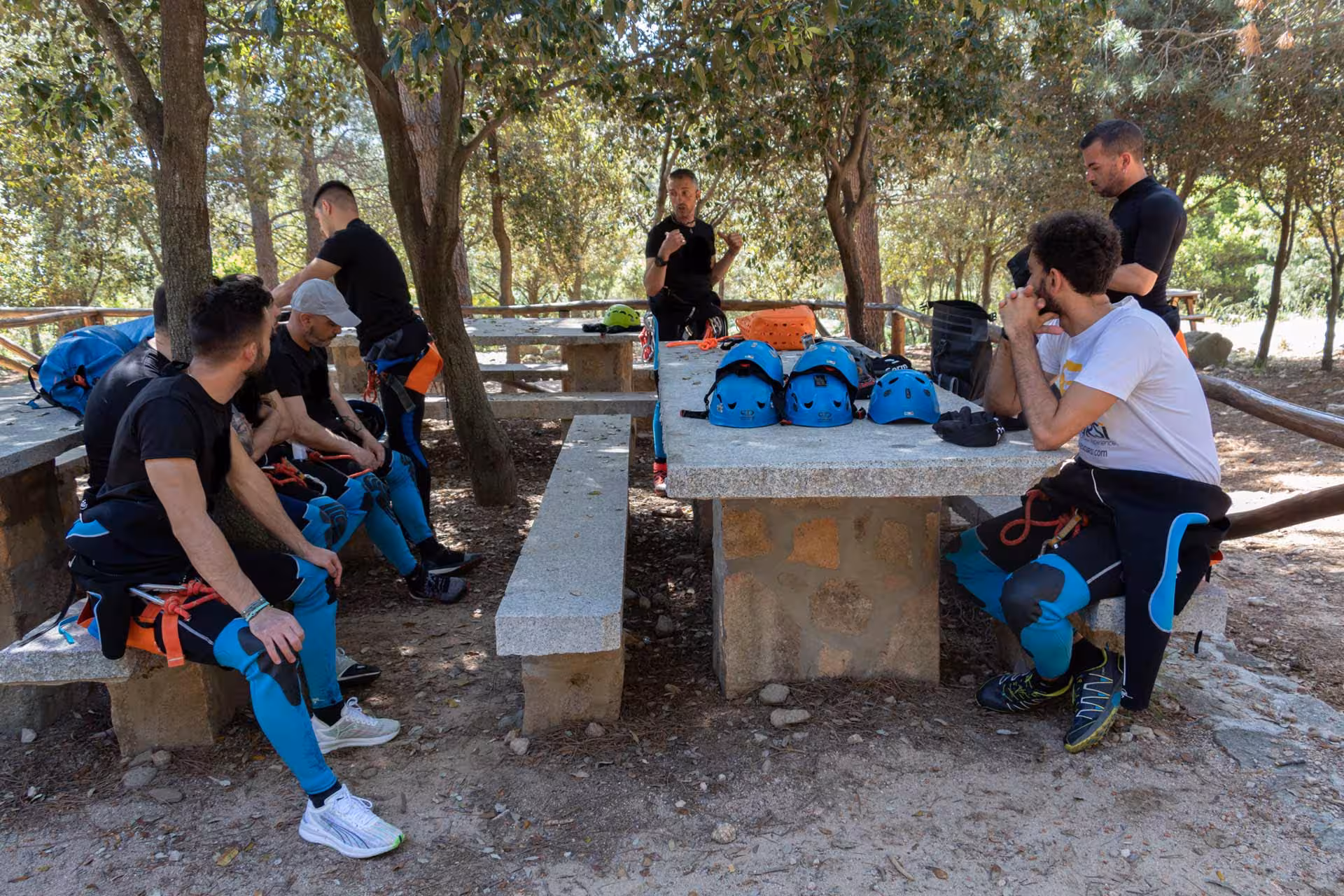 Group of adventurers preparing for canyoning in San Teodoro's Rio Pitrisconi, sitting at a picnic table with gear.