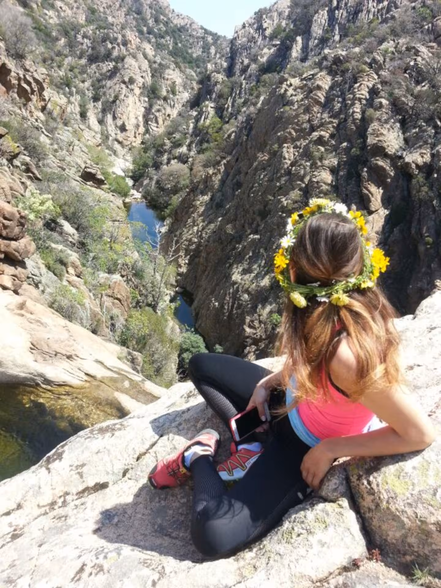 Hiker with flower crown enjoys scenic view of Rio Pitrisconi canyon during San Teodoro trekking adventure.