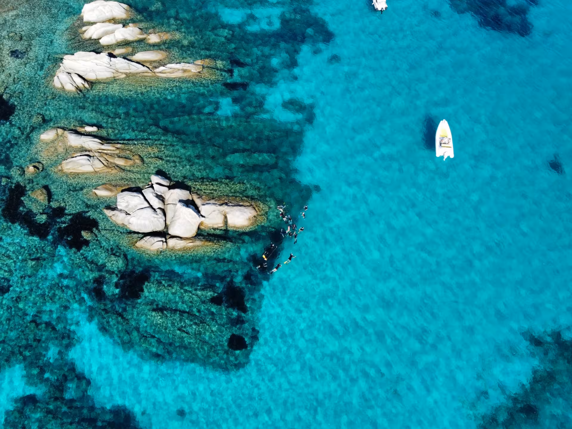 Snorkelers explore vibrant turquoise waters around Molara's rocky formations, perfect for a San Teodoro tour.