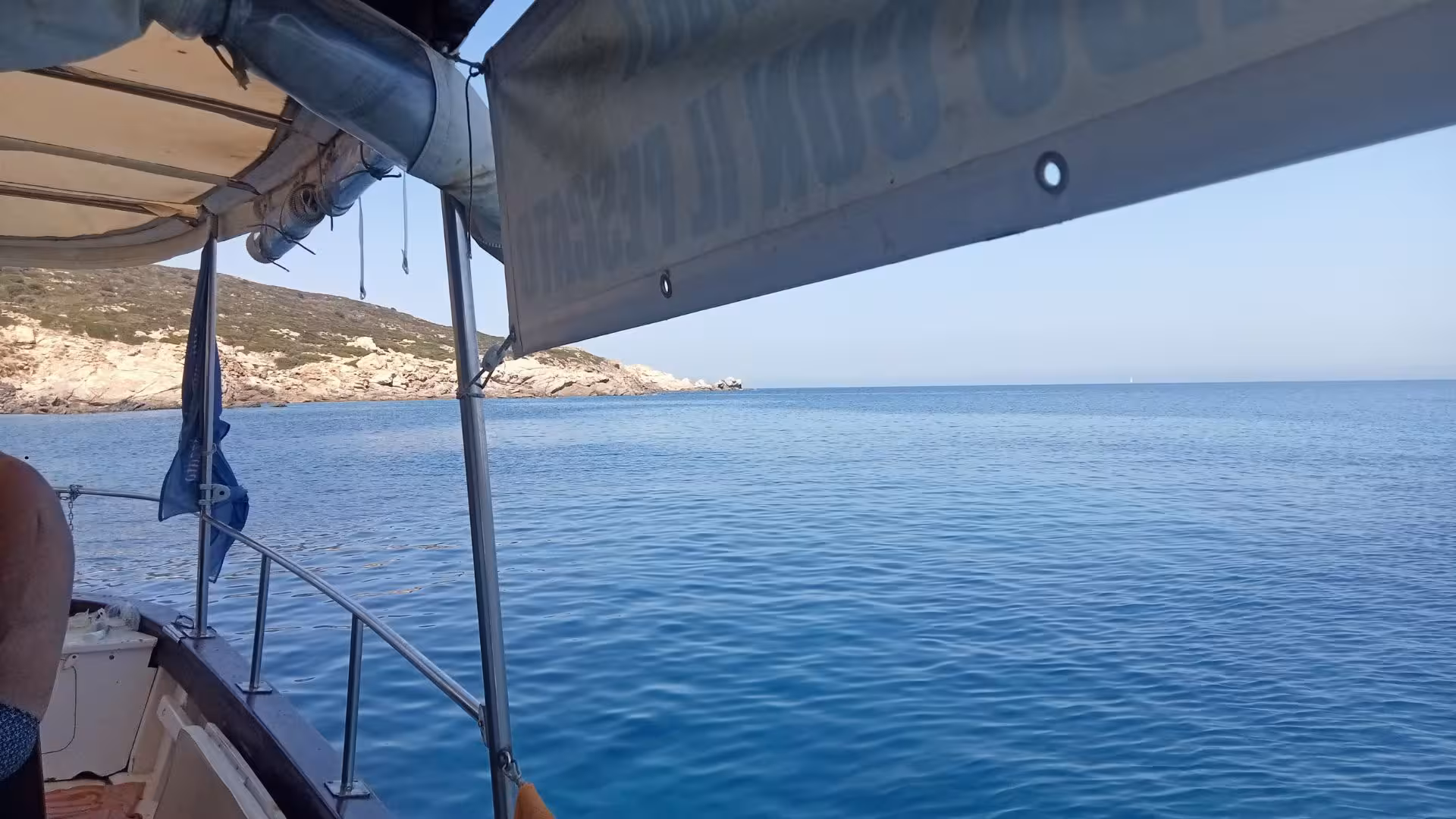 Serene boat excursion view from San Teodoro to Tavolara, showcasing clear blue waters and rocky coastline.
