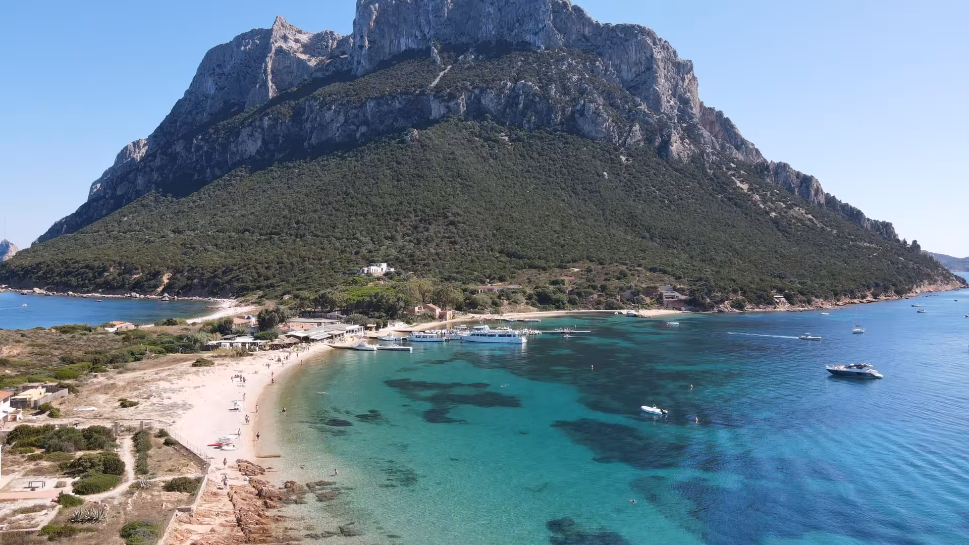 Stunning aerial view of Tavolara Island's majestic cliffs and pristine beaches, a highlight of San Teodoro fishing tour.