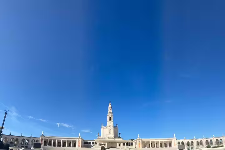 Majestic view of the Sanctuary of Fátima's main basilica under a clear blue sky, a key pilgrimage site in Portugal.