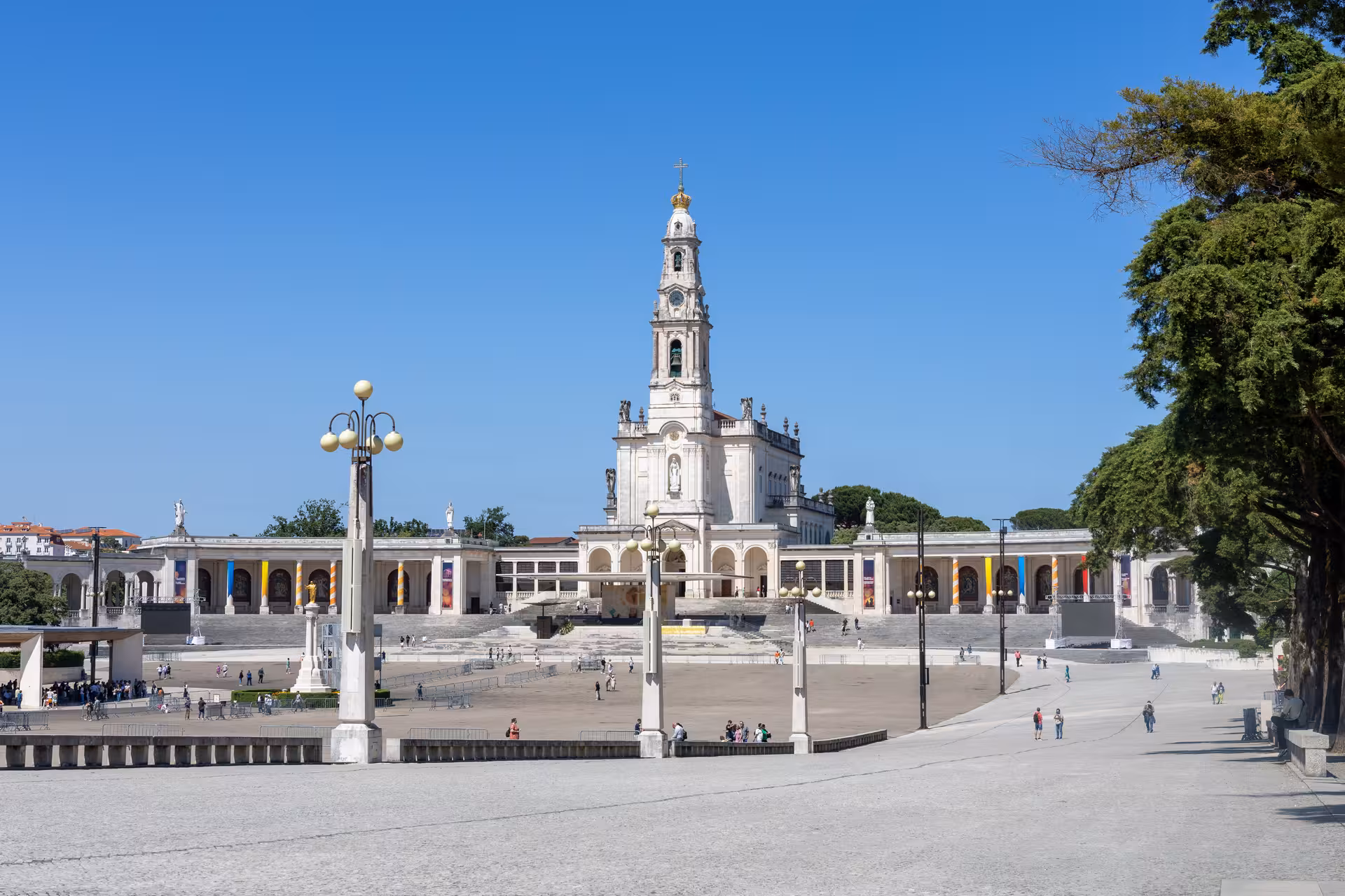 The striking facade of the Sanctuary of Fátima under a clear blue sky, highlighting its grandeur and significance.