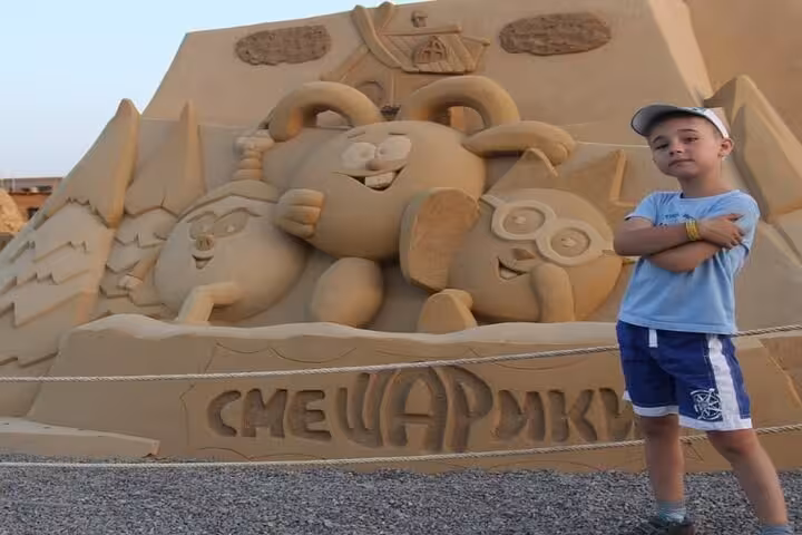 Family-friendly Sand City Hurghada tour photo with cartoon sand sculpture and private transfer tickets