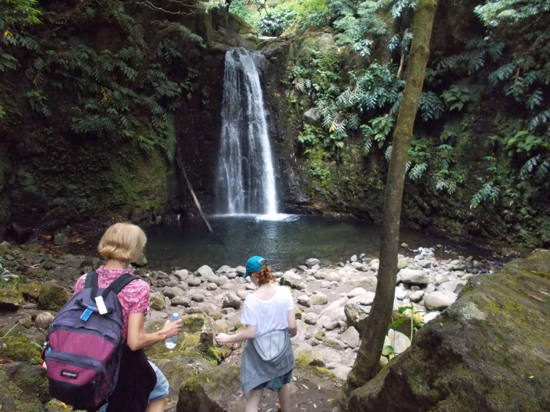 Hikers reaching a secluded waterfall lagoon on the Sanguinho Walking Tour all day in São Miguel, Azores