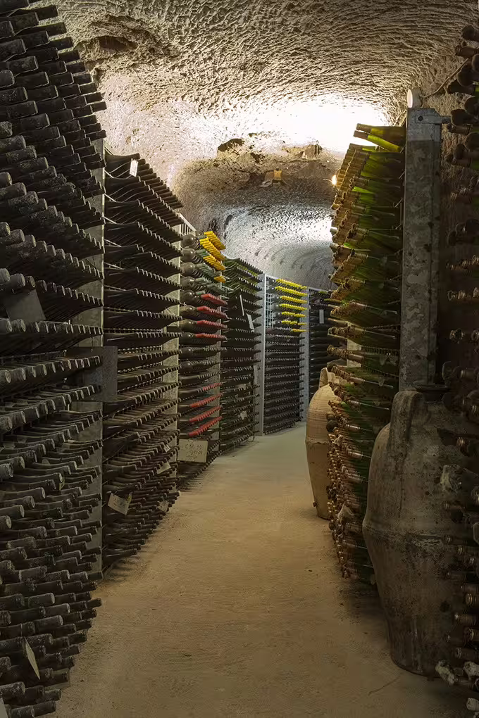 Historic underground wine cellar in Sant'Agata de' Goti with aging bottles lining stone walls for guided tasting visits