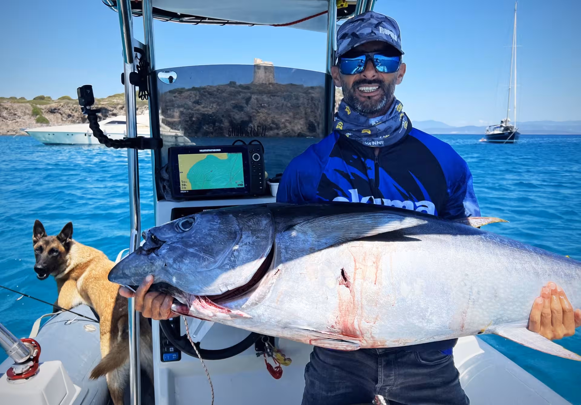 Enthusiastic fisherman showcases a large catch on a Sant'Antioco fishing trip, with a scenic coastline backdrop.