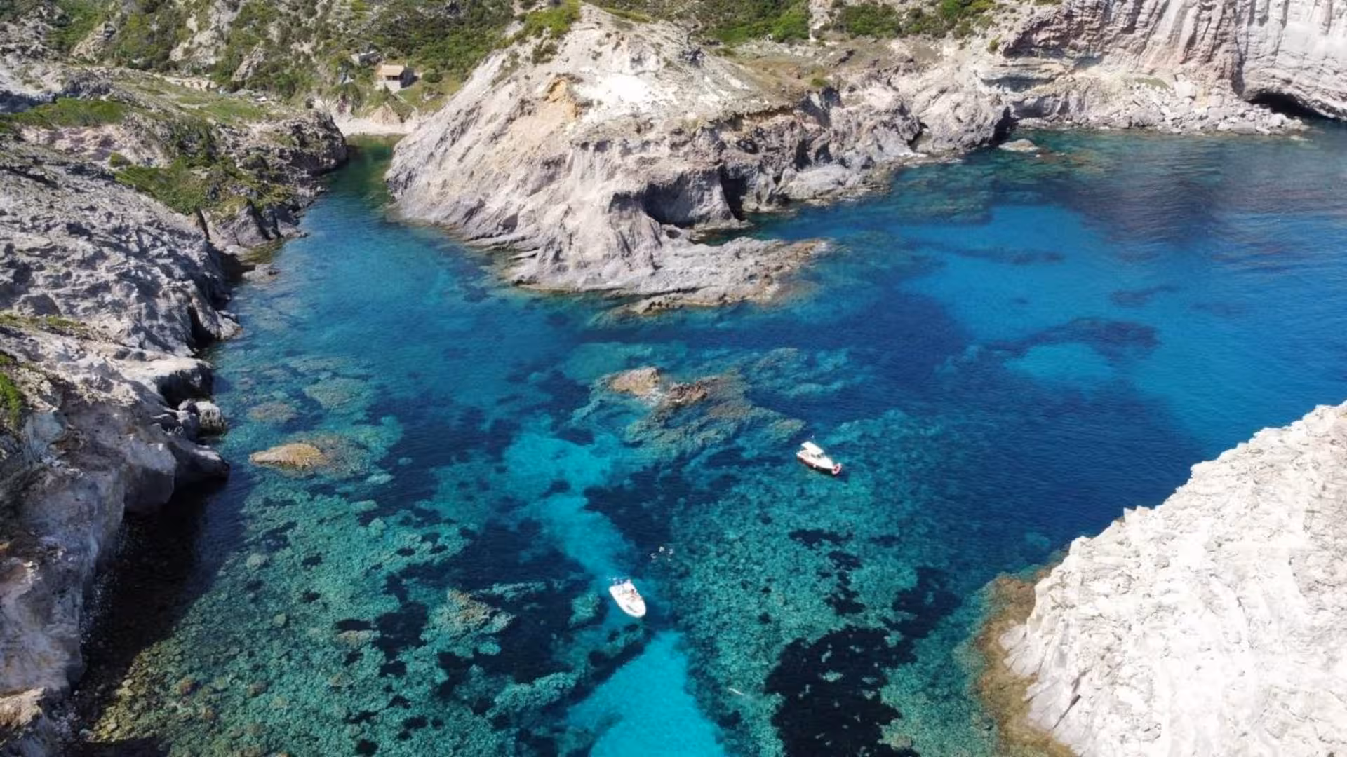Aerial view of stunning rocky coastline and crystal-clear waters near Masua, showcasing the beauty of a Sant'Antioco RIB tour.