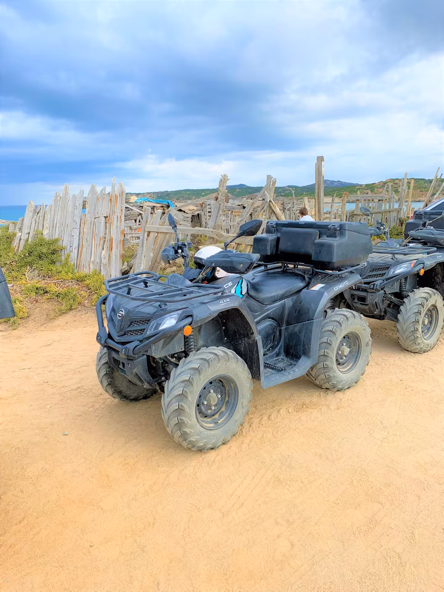 Two ATVs ready for adventure against a rustic wooden backdrop in Santa Teresa di Gallura.