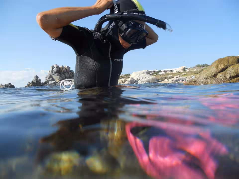 Snorkeler adjusting mask near vibrant coral in Santa Teresa di Gallura's coastal waters, ready for exploration.