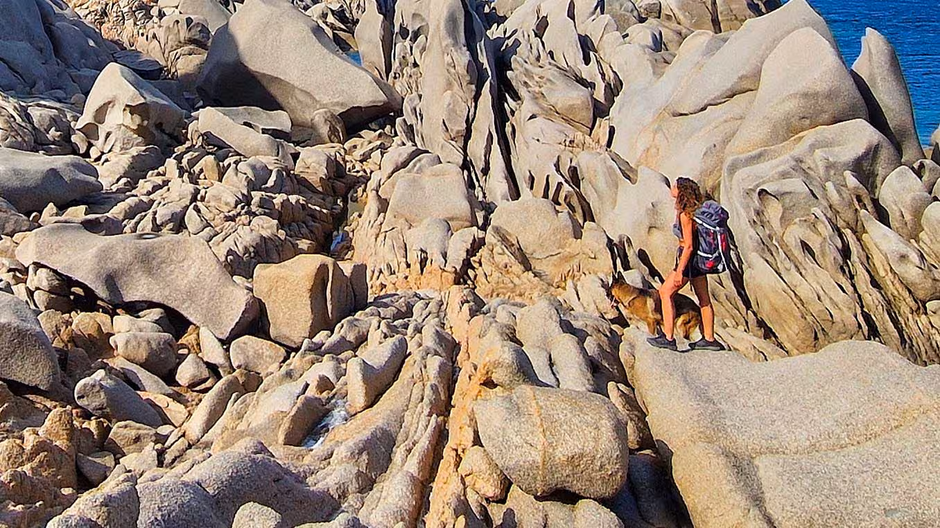 Hiker explores the rugged rock formations of Valle della Luna with a scenic sea view in Santa Teresa Gallura.