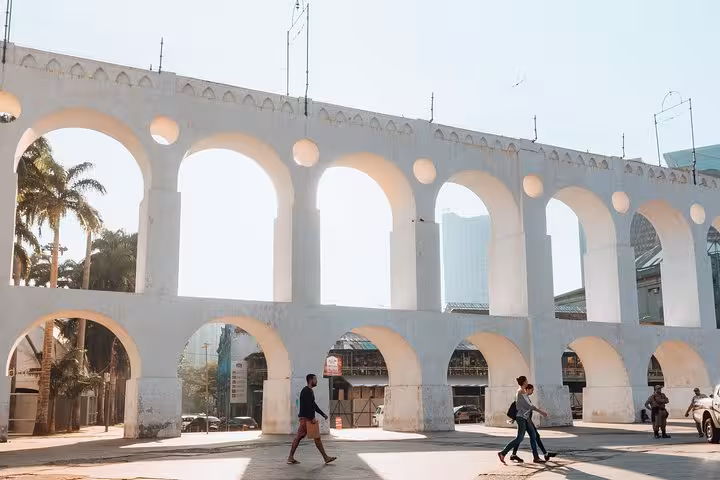 People walking by the iconic arches of Lapa in bright daylight on a private walking tour in Rio's historic district.