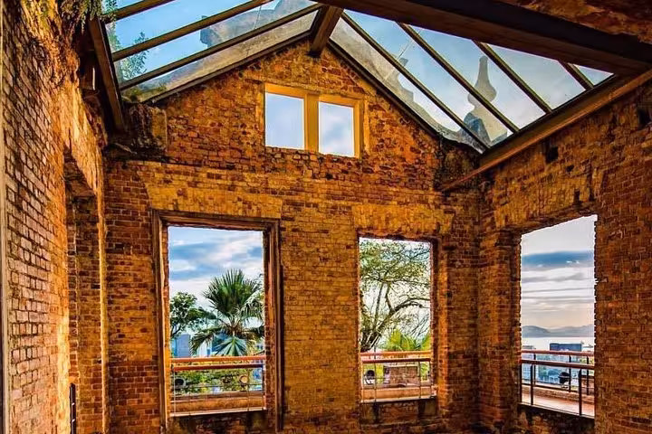 View from inside a rustic brick building in Santa Teresa with large windows overlooking lush greenery and cityscape.