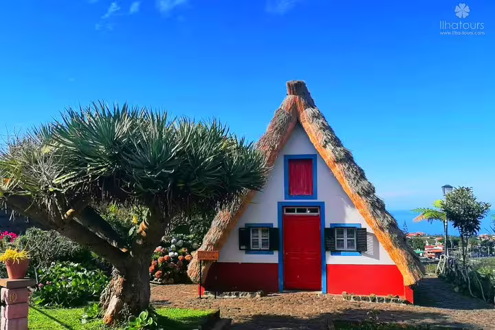 Charming Santana house with a thatched roof in Madeira, surrounded by lush greenery, ideal for cultural exploration tours.